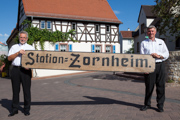 Ortsbürgermeister Dr. Werner Dahmen und Gerhard  Kneib mit dem Originalschild der »Station Zornheim« aus dem Ersten Weltkrieg, das 2009 wiederentdeckt wurde.